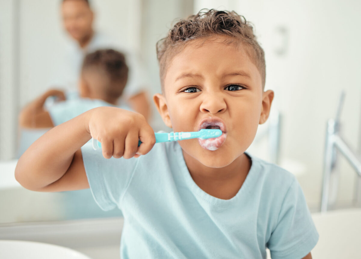 A young boy brushing his teeth at the bathroom basin